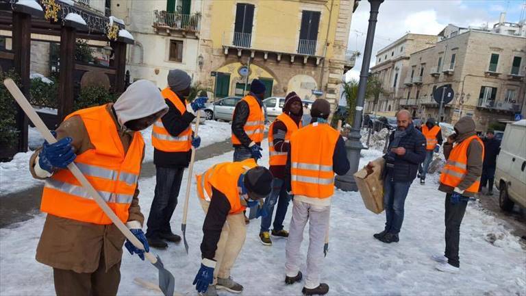 migranti spalano neve